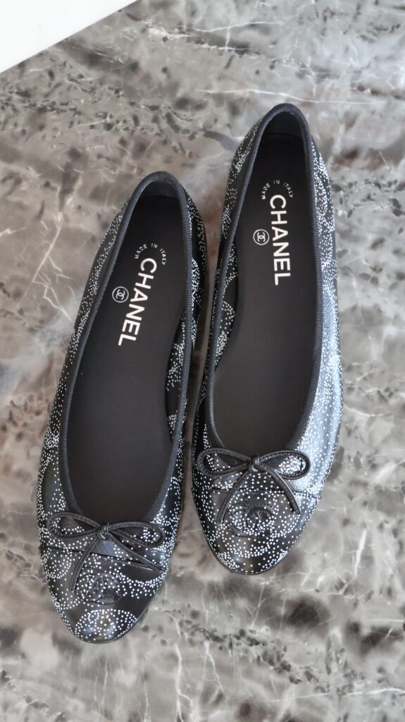 Czarne baleriny Chanel Limited Edition ze srebrzystym wzorem, kokardkami i logo CC na noskach.
