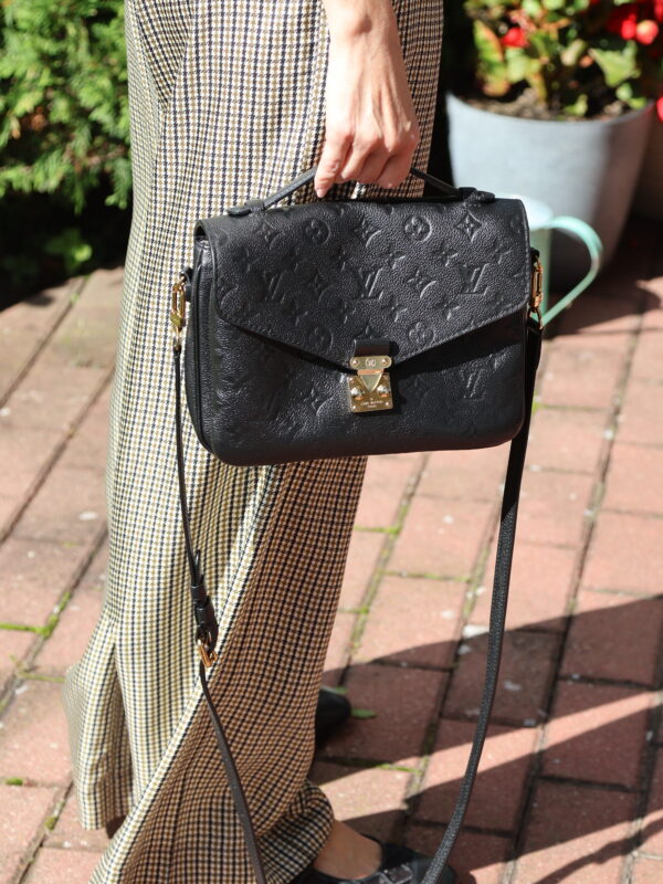 Czarna torebka Louis Vuitton Pochette Métis ze skóry Monogram Empreinte, ze złotym zapięciem, uchwytem i długim paskiem na ramię.