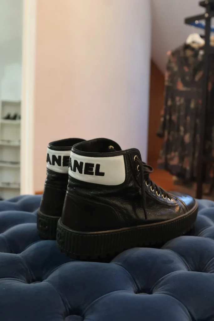 Czarne wysokie tenisówki Chanel z białym pasem i napisem CHANEL przy kostce